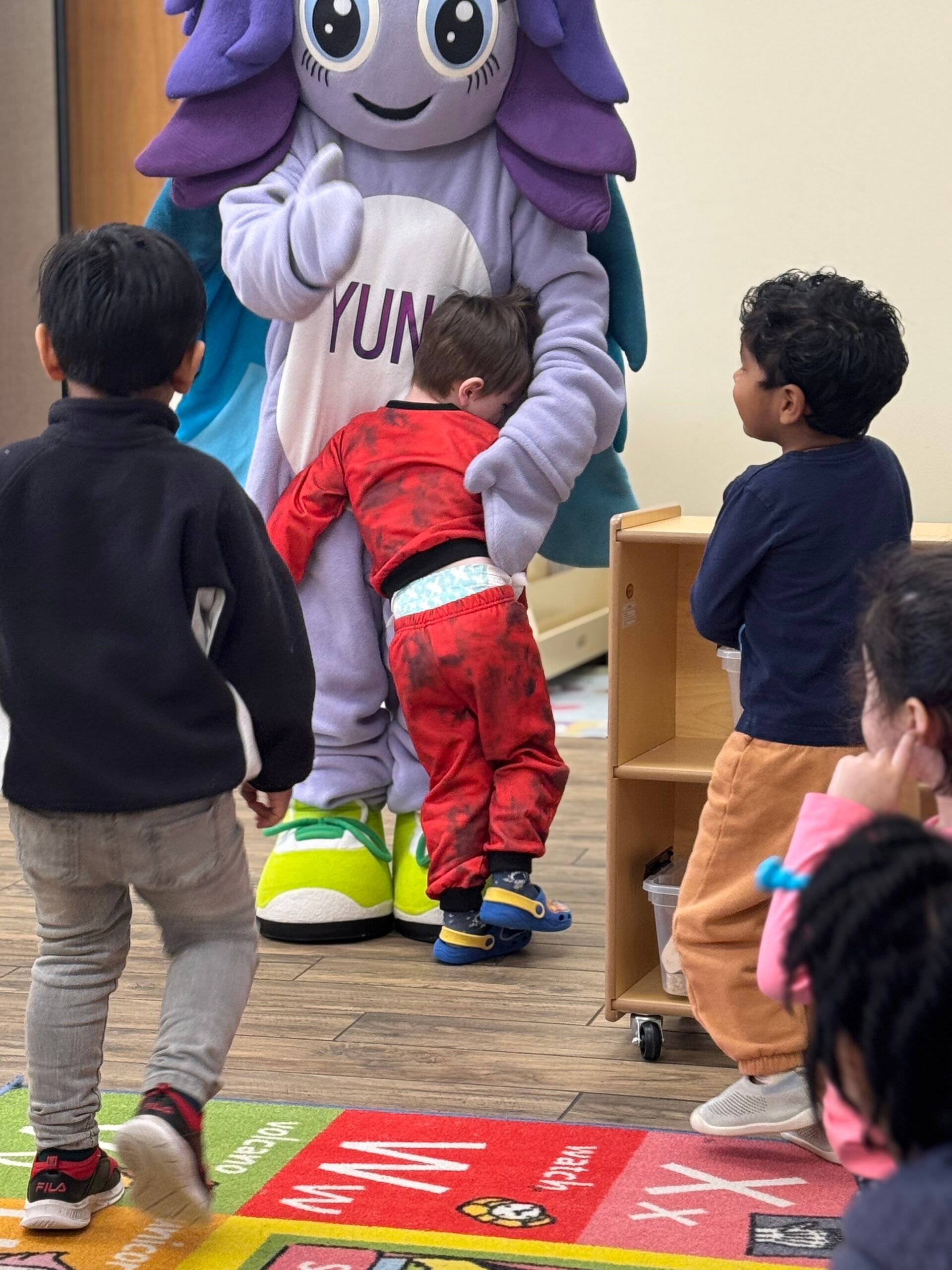 Children giving the Yuna mascot a big hug during a classroom visit