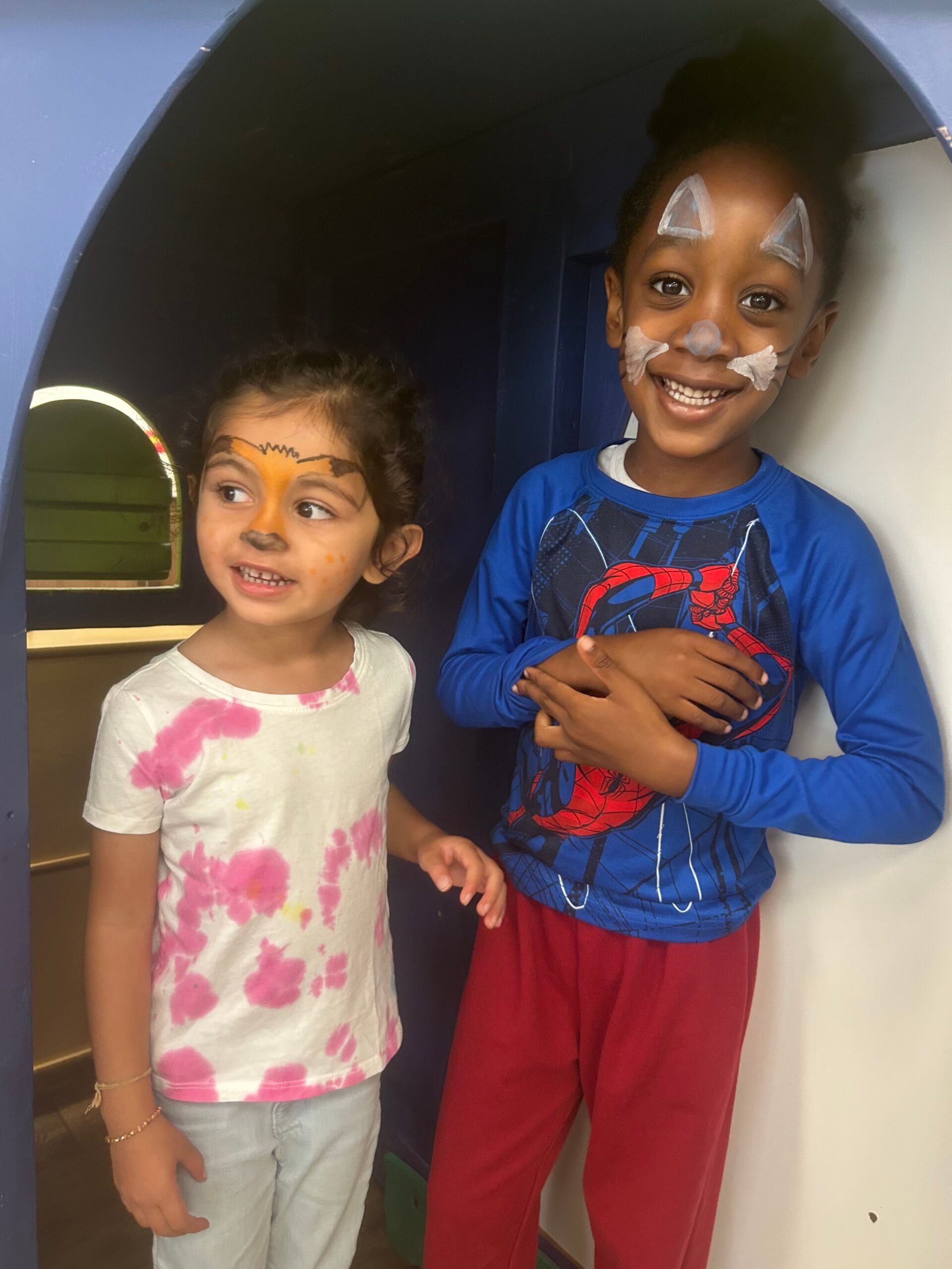 Two children with fun face paint smiling together
