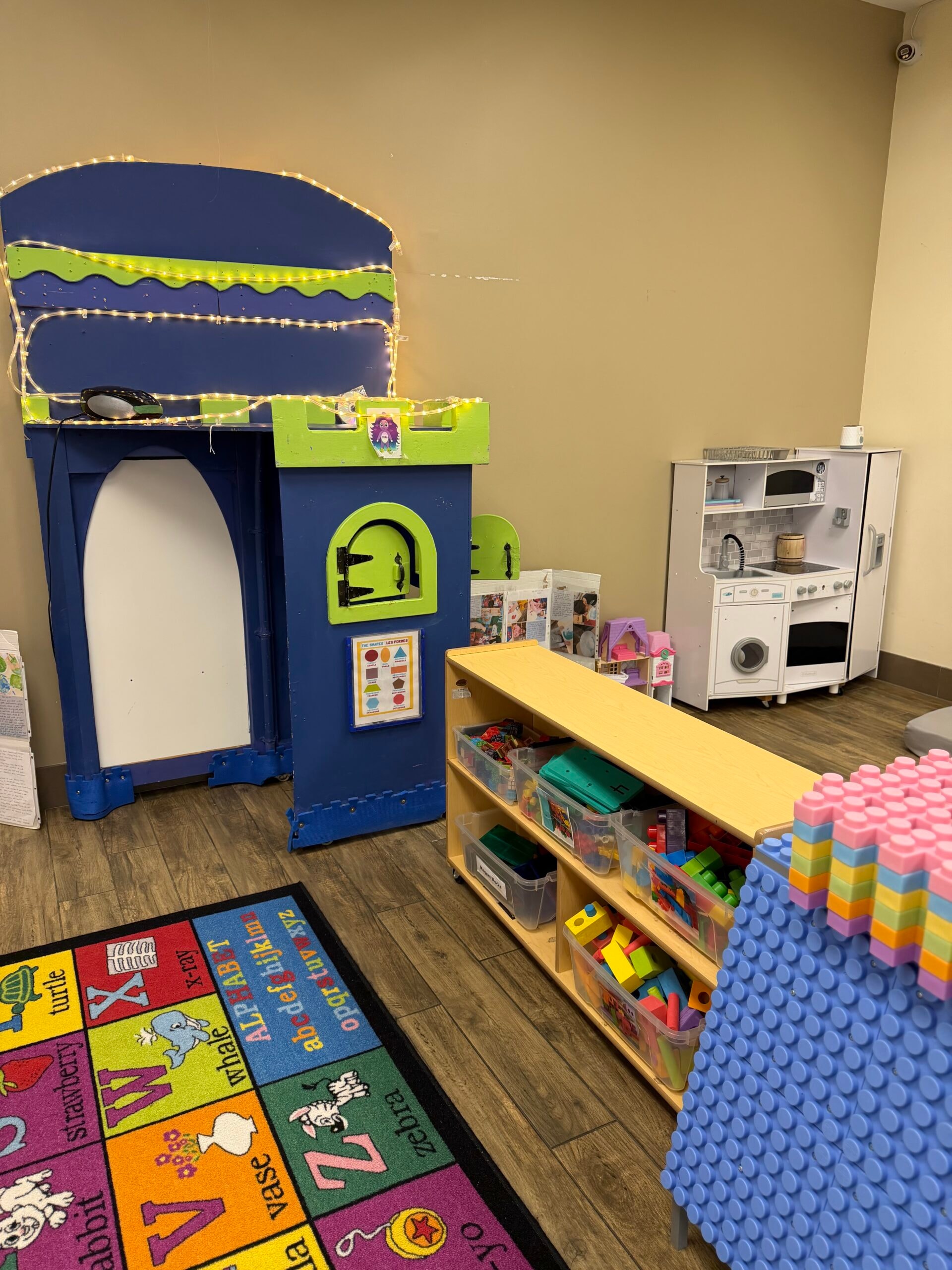 Preschool play area with castle structure, play kitchen, and dress-up rack