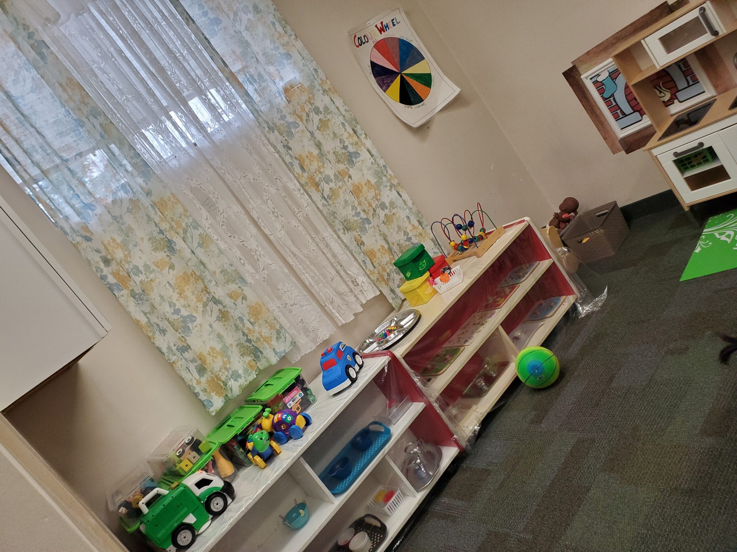 Toddler room with toy shelves, colour wheel poster, and play kitchen