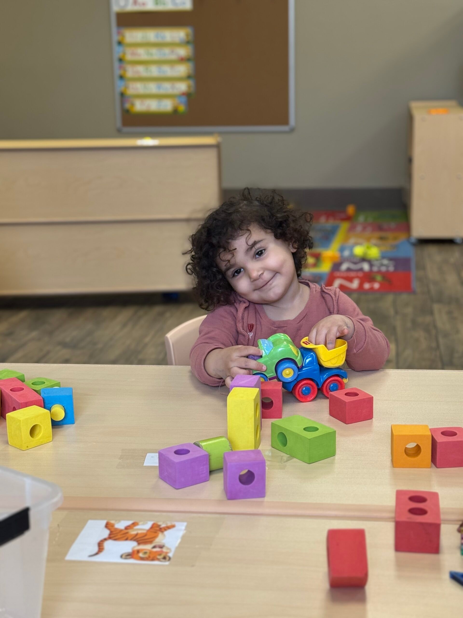 Toddler playing with colourful blocks in the classroom